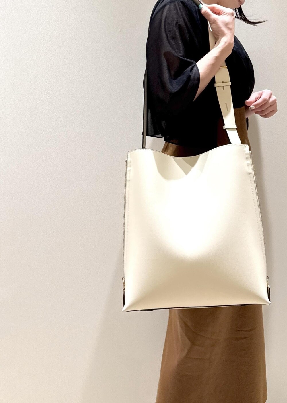 ホワイト系のショルダーバッグ、ブラック系のパンプス、ブラウン系のスカートを着用したレディースの春コーディネートの7枚目の写真