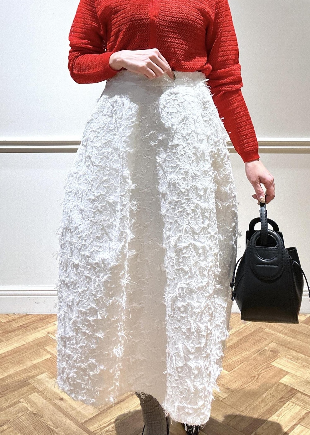 ブラック系のショルダーバッグ、ブラック系のパンプス、ホワイト系のスカートを着用したレディースの春コーディネートの5枚目の写真