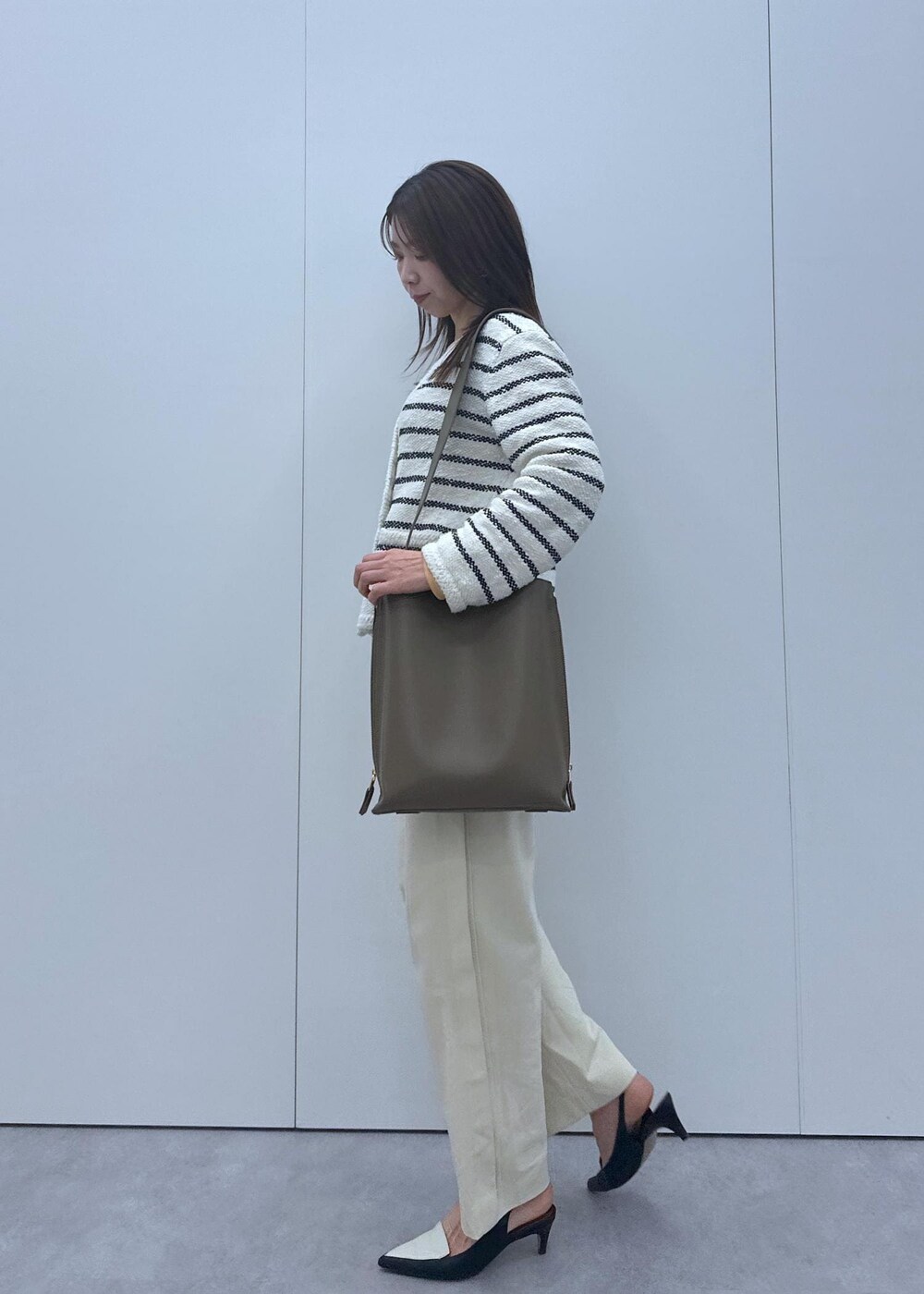 ブラック系のパンプス、ホワイト系のノーカラージャケット、オレンジ系のTシャツ/カットソーを着用したレディースの冬コーディネートの3枚目の写真