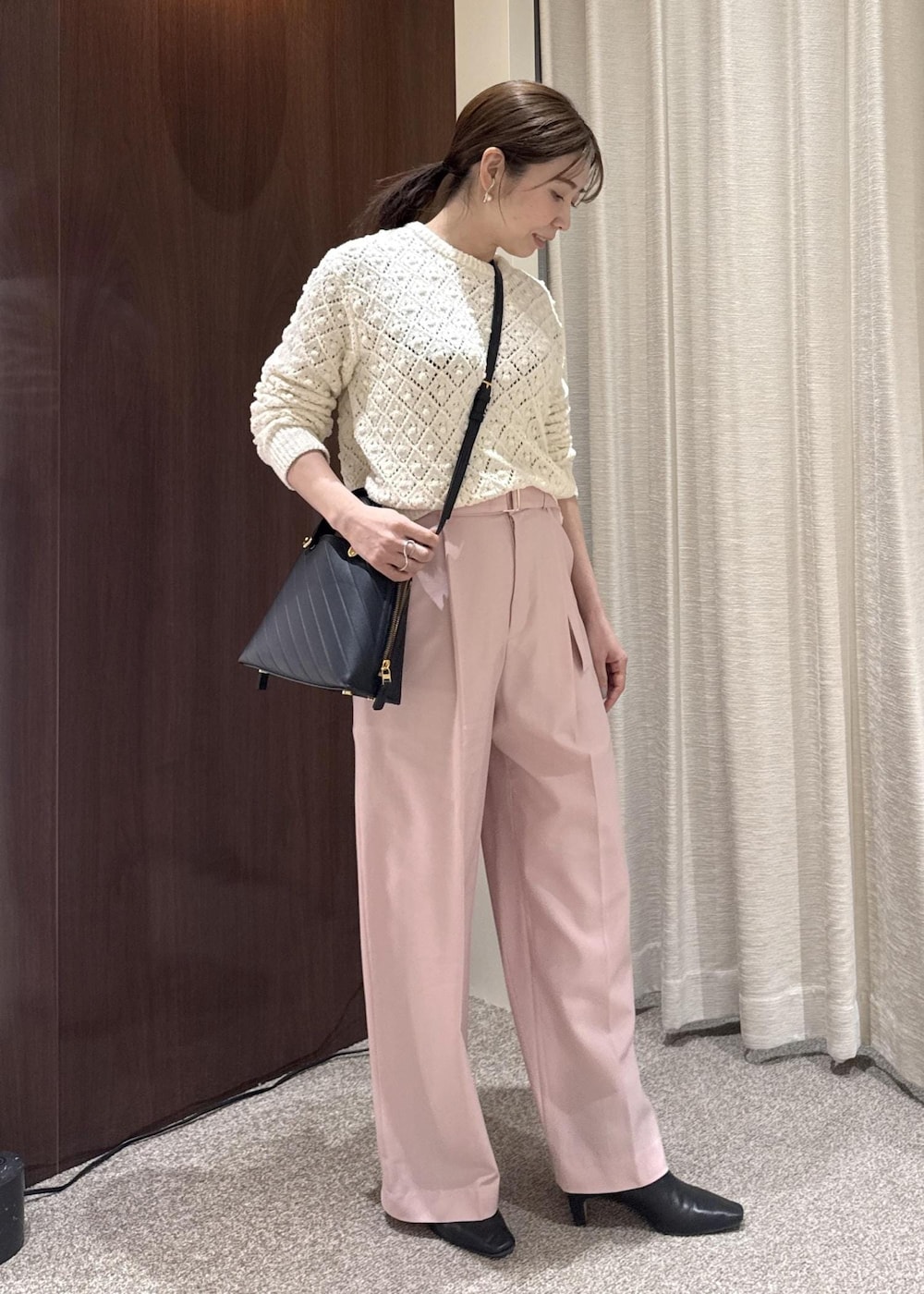 ブラック系のブーツ、ブラック系のハンドバッグ、ホワイト系のニット/セーターを着用したレディースの冬コーディネートの3枚目の写真