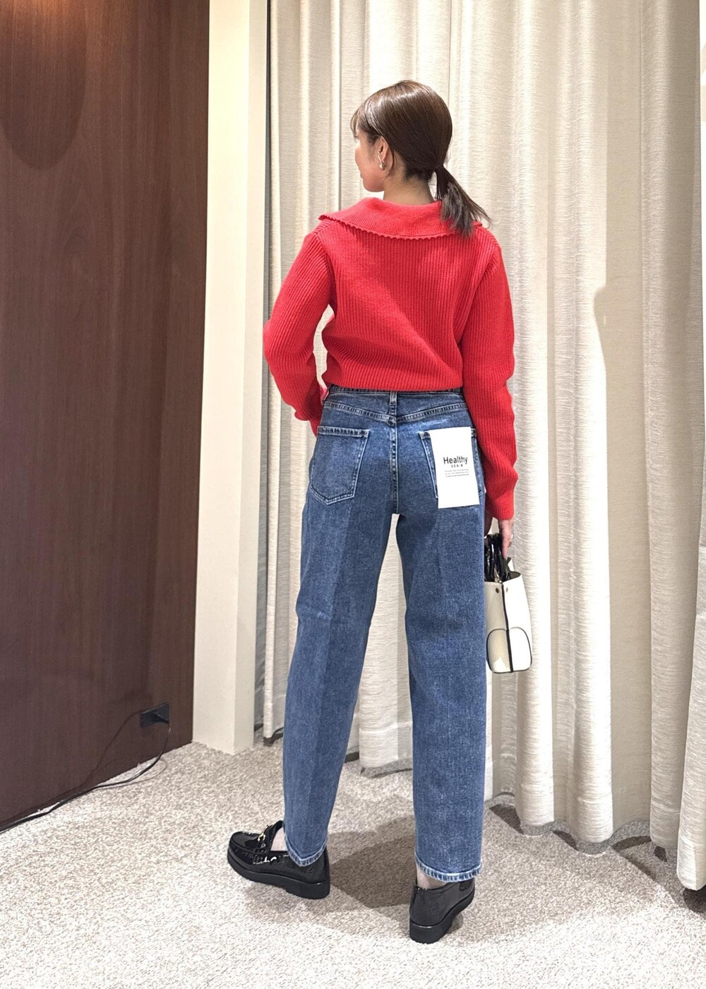 ホワイト系のハンドバッグ、レッド系のニット/セーター、ブラック系のローファーを着用したレディースの冬コーディネートの2枚目の写真