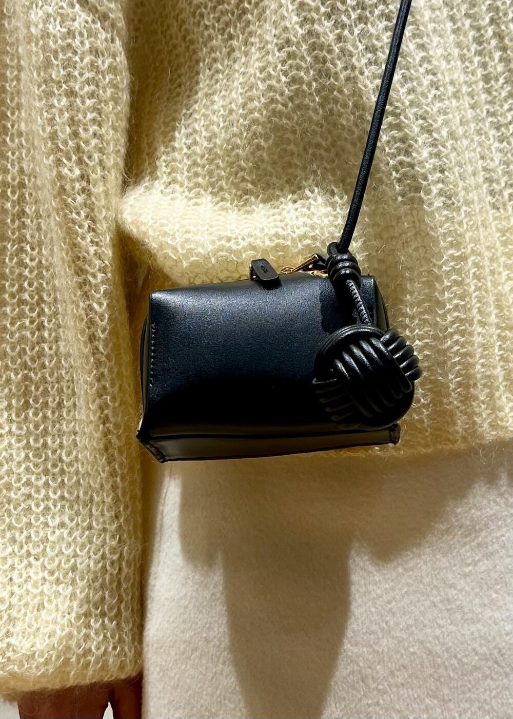 ホワイト系のスカート、イエロー系のニット/セーター、ホワイト系のTシャツ/カットソーを着用したレディースの冬コーディネートの8枚目の写真