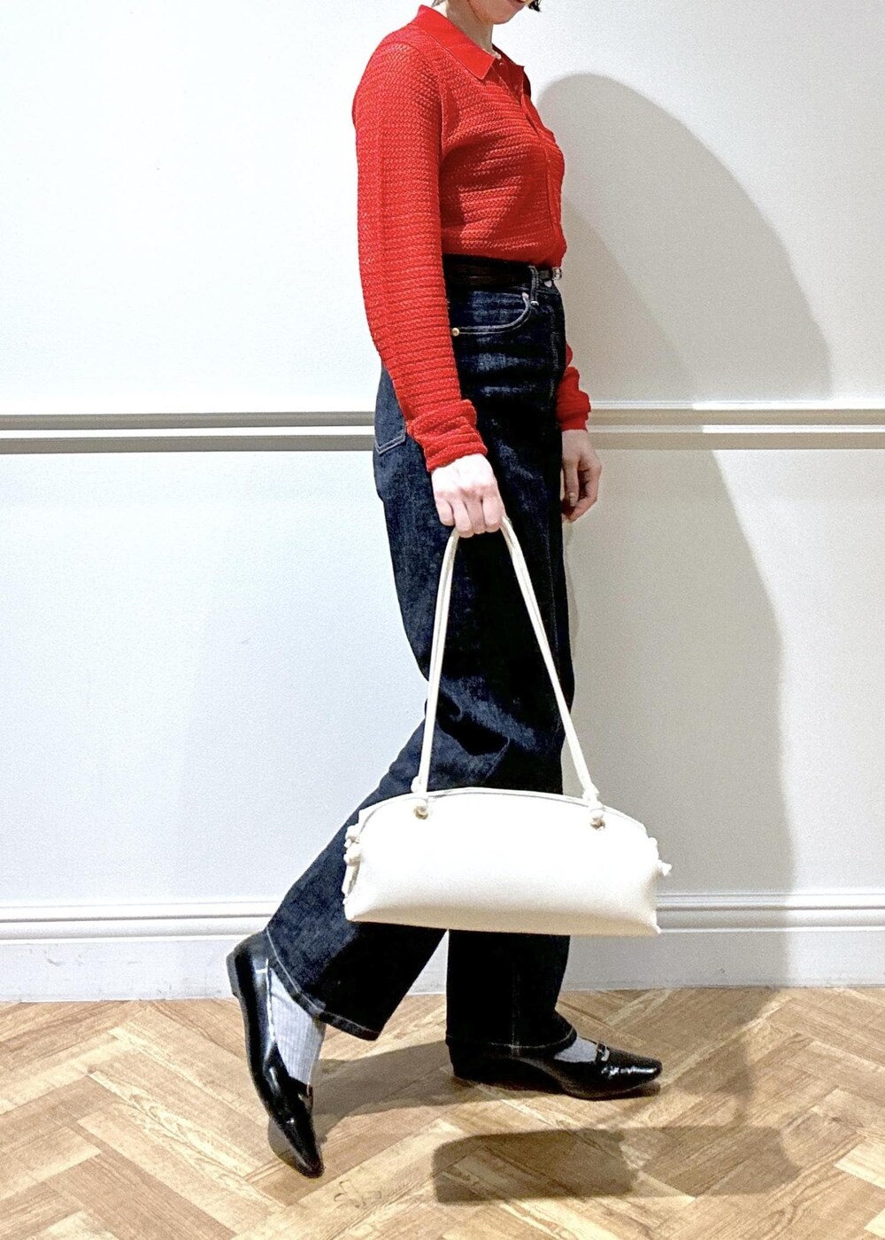 ブラック系のパンプス、ホワイト系のハンドバッグ、レッド系のカーディガン/ボレロを着用したレディースの冬コーディネートの2枚目の写真
