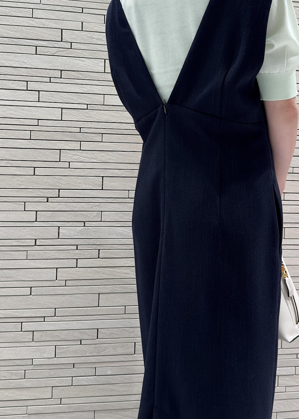 グリーン系のニット/セーター、ブラウン系のパンプス、ブルー系のジャンパースカートを着用したレディースの夏コーディネートの4枚目の写真