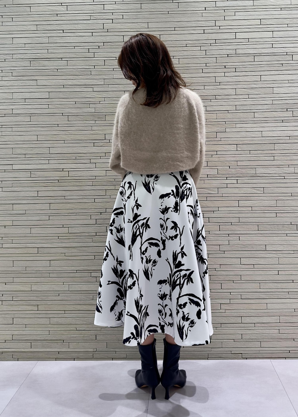 パープル系のハンドバッグ、ブラック系のブーツ、ベージュ系のニット/セーターを着用したレディースの秋コーディネートの3枚目の写真