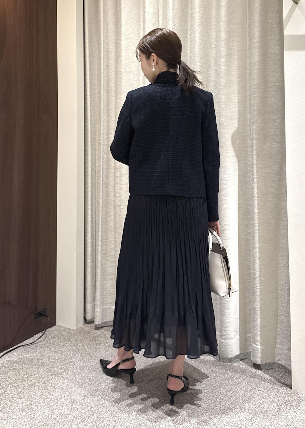 ブルー系のワンピース、グレー系のハンドバッグ、ブルー系のノーカラージャケットを着用したレディースの冬コーディネートの3枚目の写真