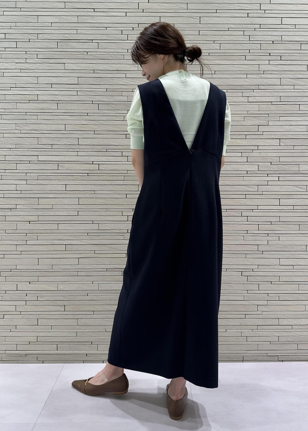 グリーン系のニット/セーター、ブラウン系のパンプス、ブルー系のジャンパースカートを着用したレディースの夏コーディネートの3枚目の写真