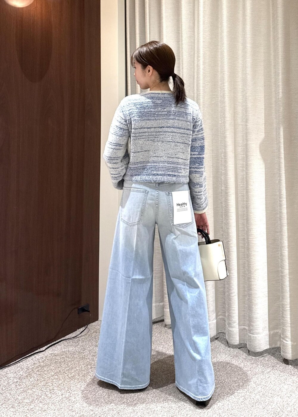 ブラック系のブーツ、ホワイト系のハンドバッグを着用したレディースの冬コーディネートの3枚目の写真