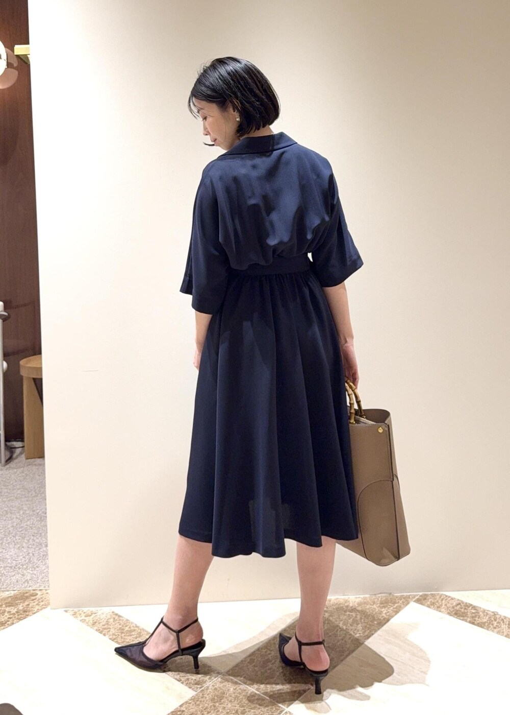 ブラック系のパンプス、ブルー系のワンピース、ベージュ系のトートバッグを着用したレディースの夏コーディネートの3枚目の写真