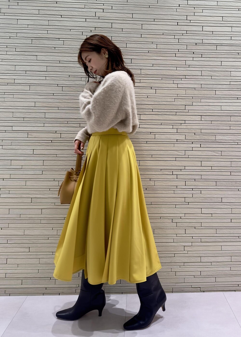 ブラック系のブーツ、ブラック系のその他アウター、イエロー系のハンドバッグを着用したレディースの冬コーディネートの7枚目の写真