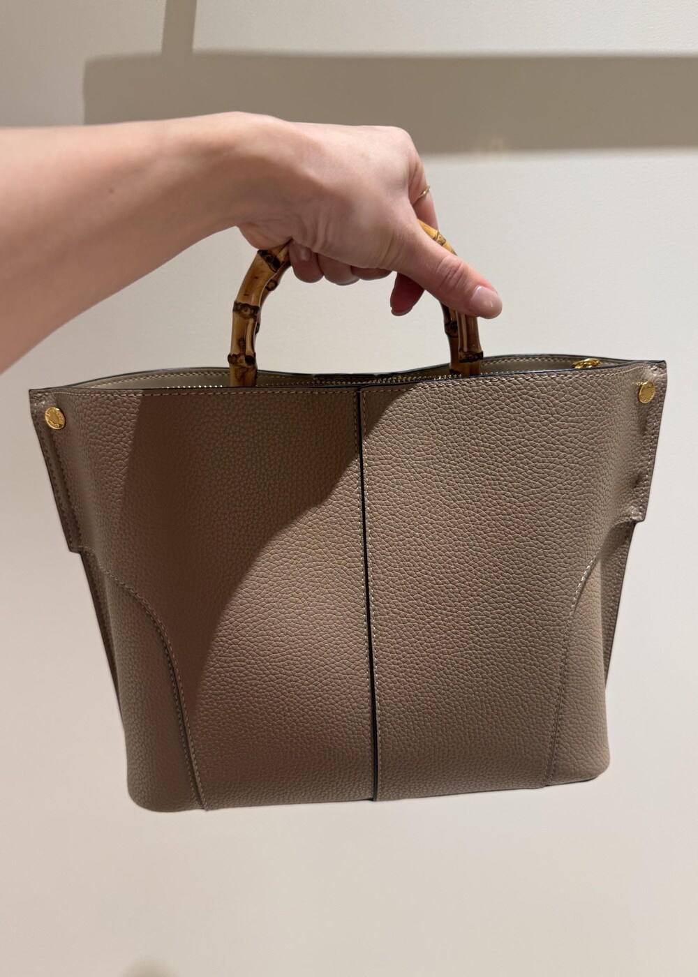 ブラック系のスカート、ベージュ系のハンドバッグ、ブラック系のブーツを着用したレディースの秋コーディネートの9枚目の写真