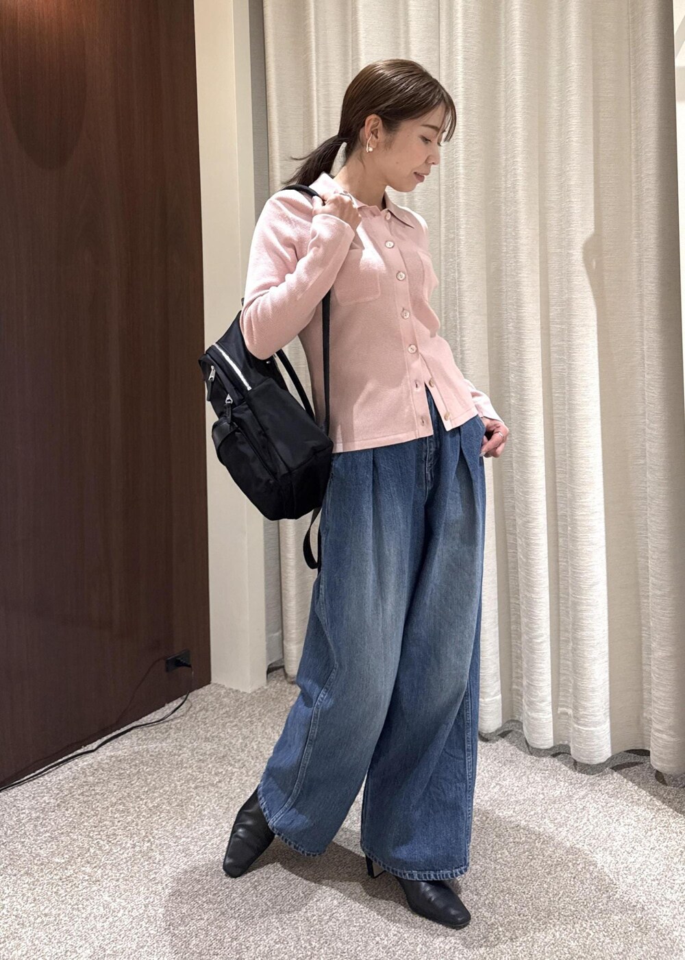 ブルー系のデニムパンツ、ブラック系のブーツ、ブラック系のバックパック/リュックを着用したレディースの冬コーディネートの2枚目の写真