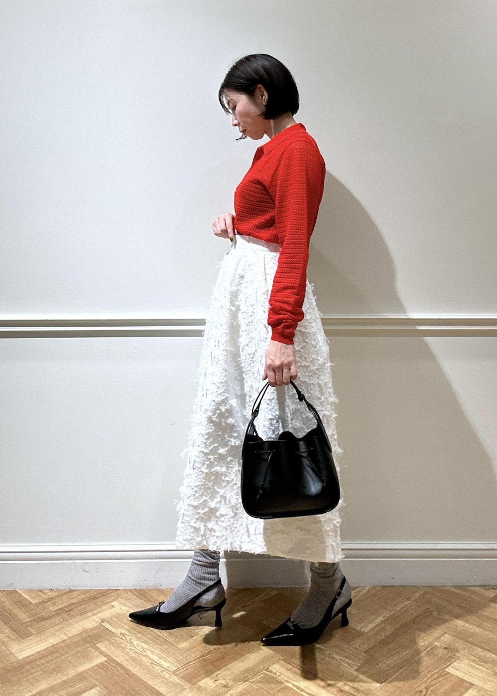 ブラック系のショルダーバッグ、ブラック系のパンプス、ホワイト系のスカートを着用したレディースの春コーディネートの2枚目の写真