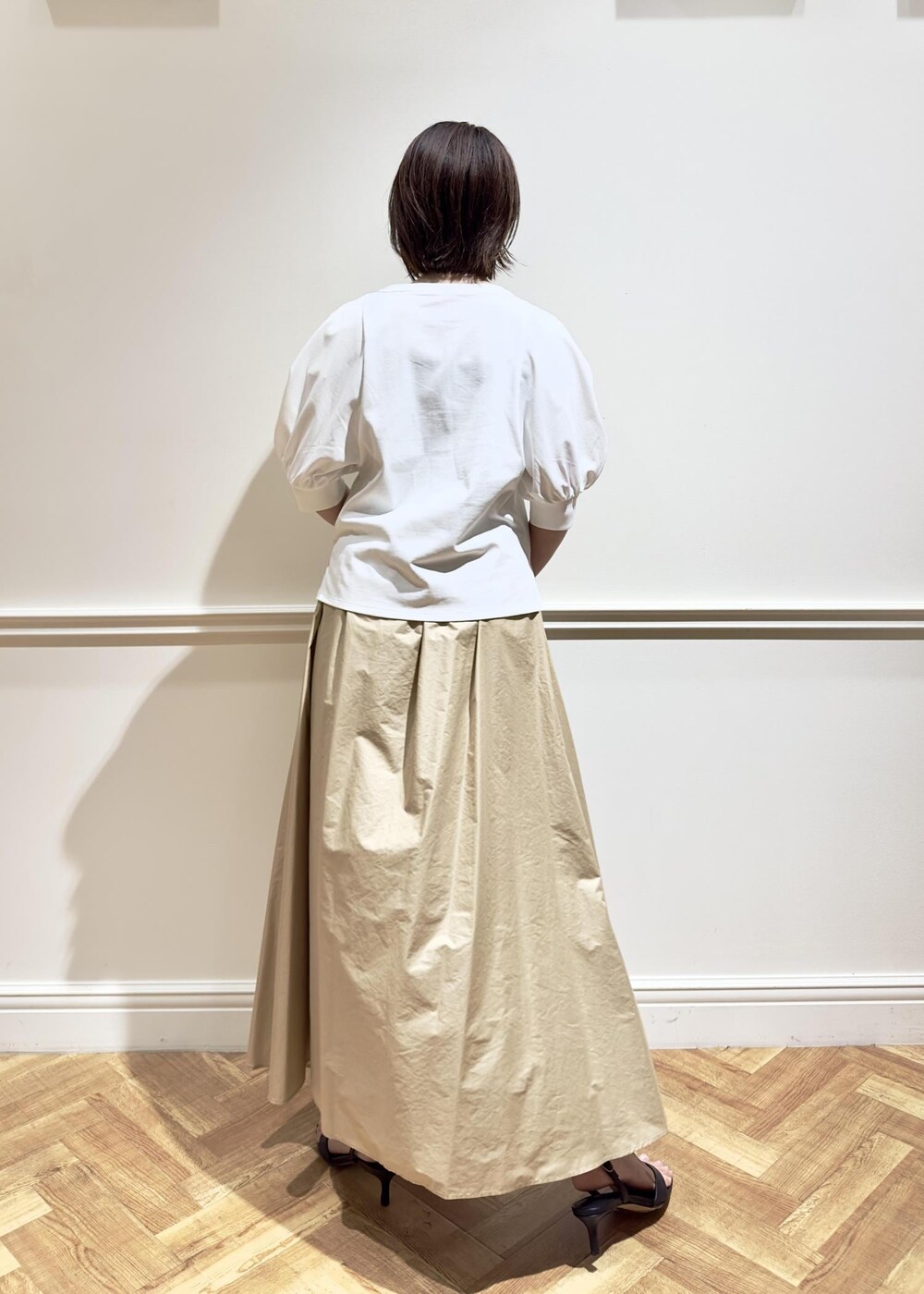 ブラック系のサンダル、ベージュ系のスカート、ホワイト系のTシャツ/カットソーを着用したレディースの夏コーディネートの2枚目の写真