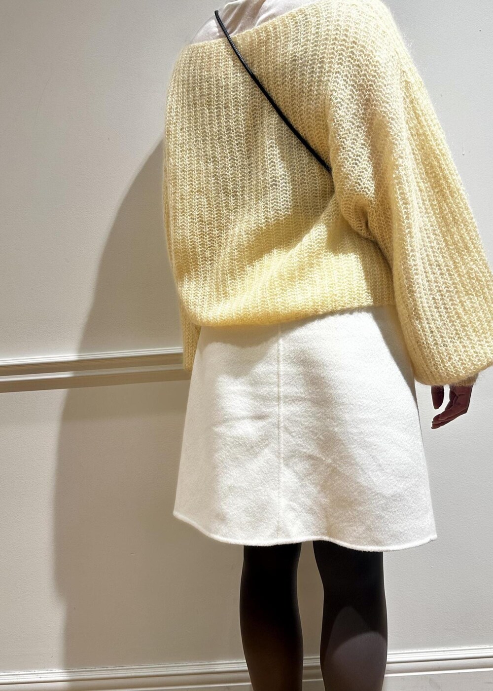 ホワイト系のスカート、イエロー系のニット/セーター、ホワイト系のTシャツ/カットソーを着用したレディースの冬コーディネートの6枚目の写真