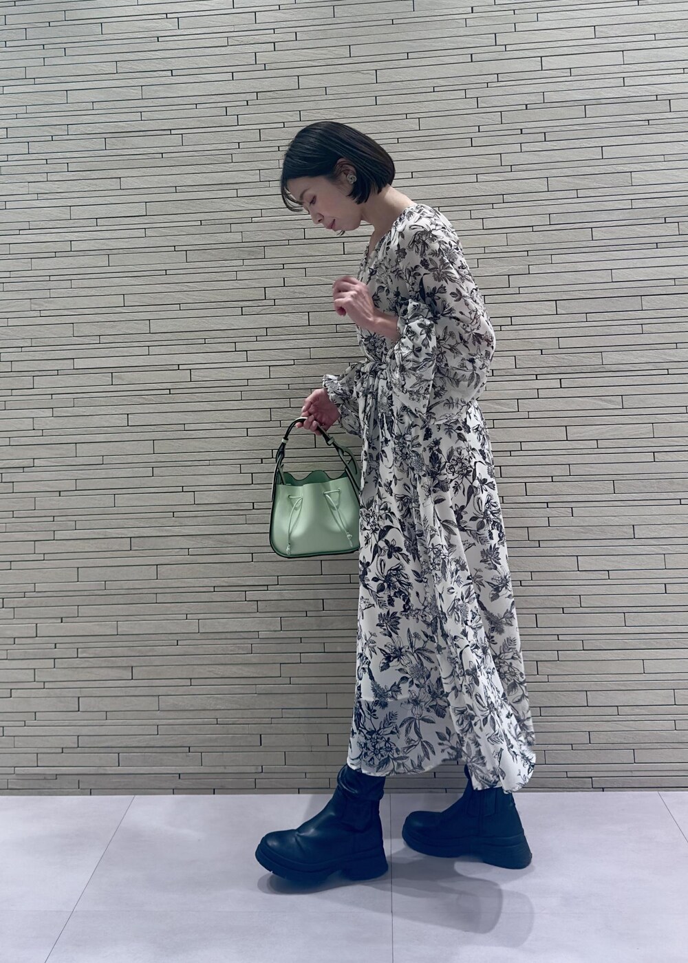 グリーン系のハンドバッグ、ブラック系のダウンジャケット/コート、ブラック系のワンピースを着用したレディースの冬コーディネートの6枚目の写真