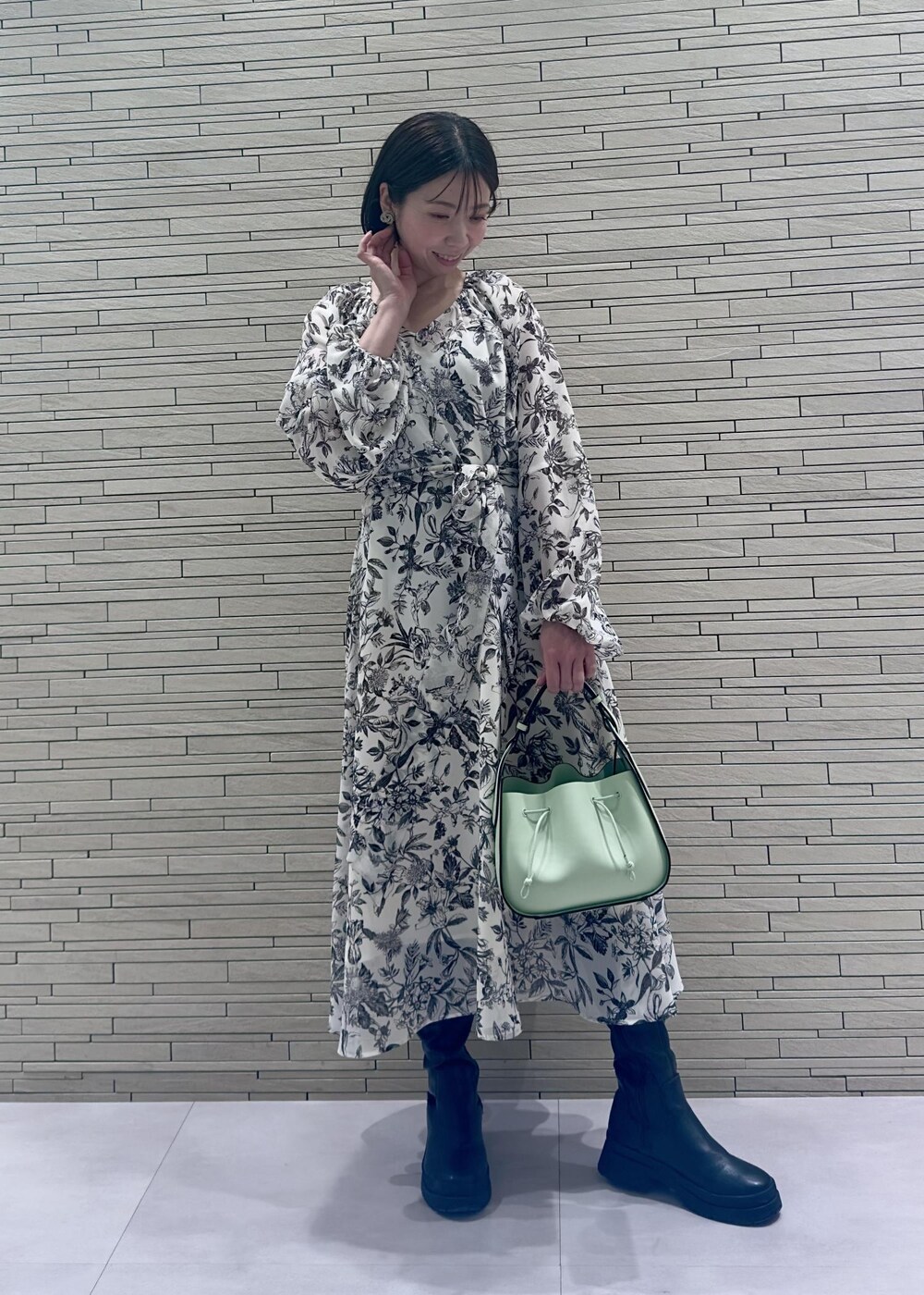 グリーン系のハンドバッグ、ブラック系のダウンジャケット/コート、ブラック系のワンピースを着用したレディースの冬コーディネートの5枚目の写真