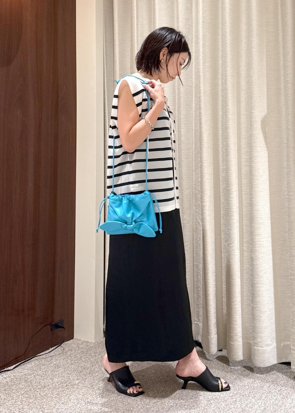 ブラック系のサンダル、ブラック系のスカート、ブルー系のシャツ/ブラウスを着用したレディースの夏コーディネートの2枚目の写真