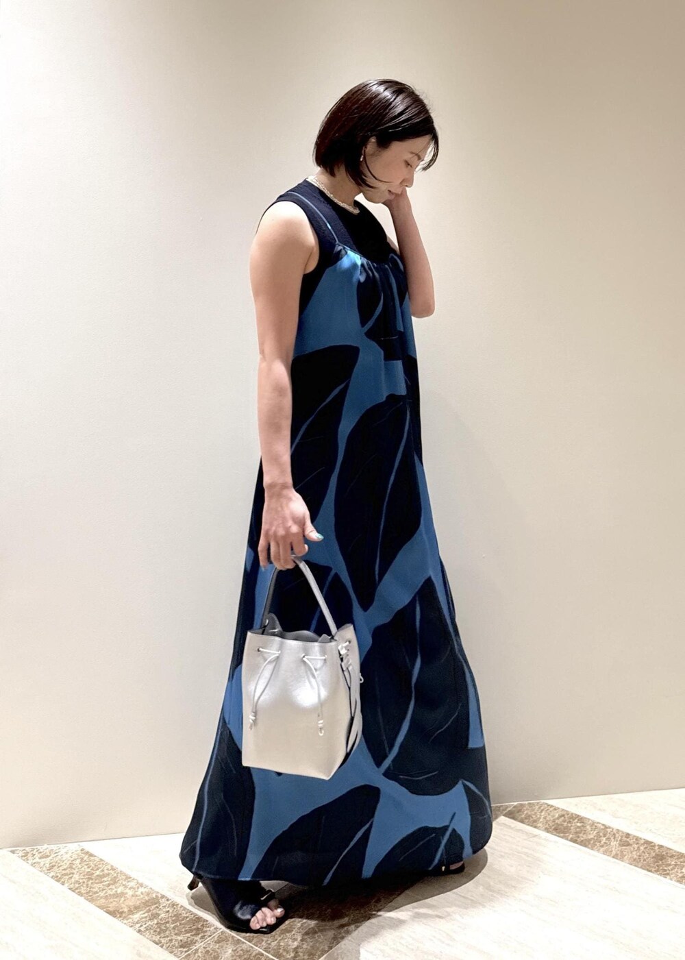 ブラック系のサンダル、シルバー系のショルダーバッグ、ブルー系のワンピースを着用したレディースの春コーディネートの2枚目の写真