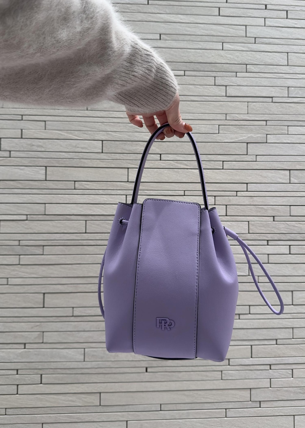 パープル系のハンドバッグ、ブラック系のブーツ、ベージュ系のニット/セーターを着用したレディースの秋コーディネートの5枚目の写真