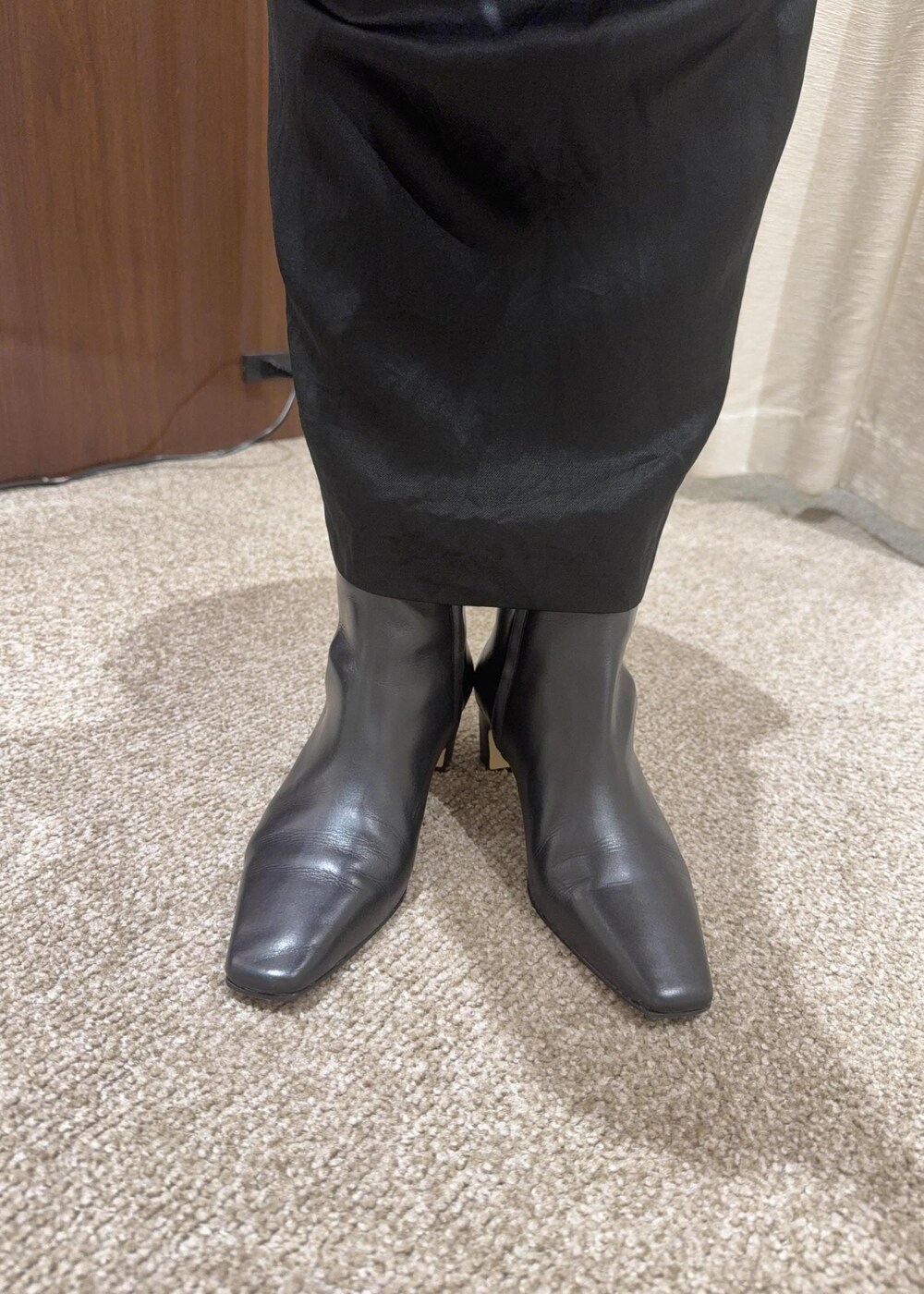 ブラック系のスカート、ベージュ系のハンドバッグ、ブラック系のブーツを着用したレディースの秋コーディネートの10枚目の写真