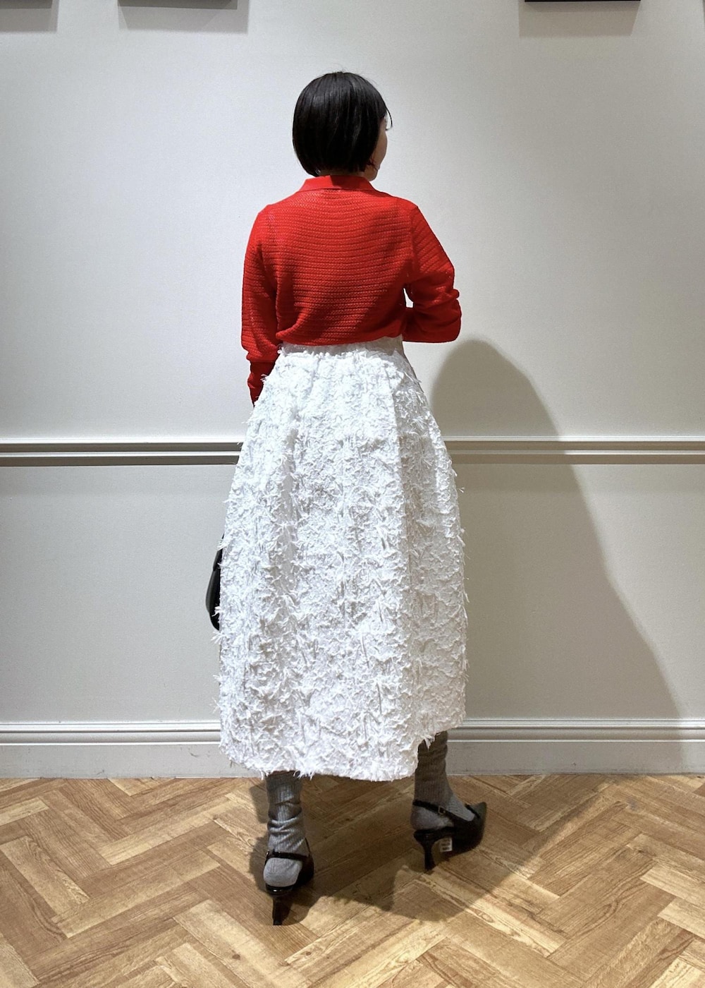 ブラック系のショルダーバッグ、ブラック系のパンプス、ホワイト系のスカートを着用したレディースの春コーディネートの3枚目の写真