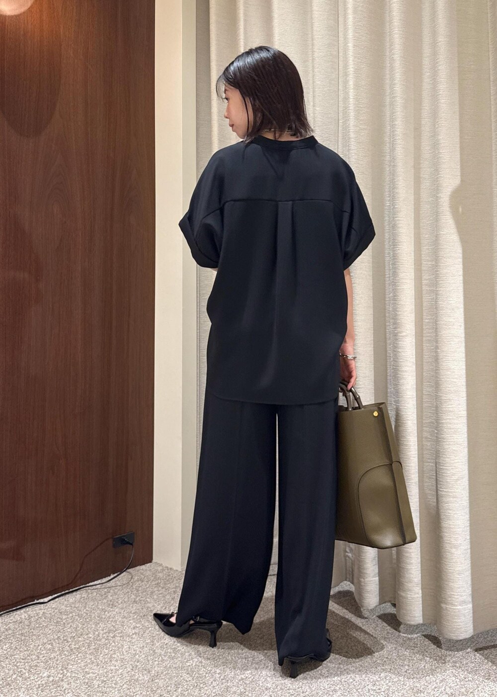 ブラック系のパンプス、グリーン系のトートバッグ、ブラック系のシャツ/ブラウスを着用したレディースの夏コーディネートの3枚目の写真