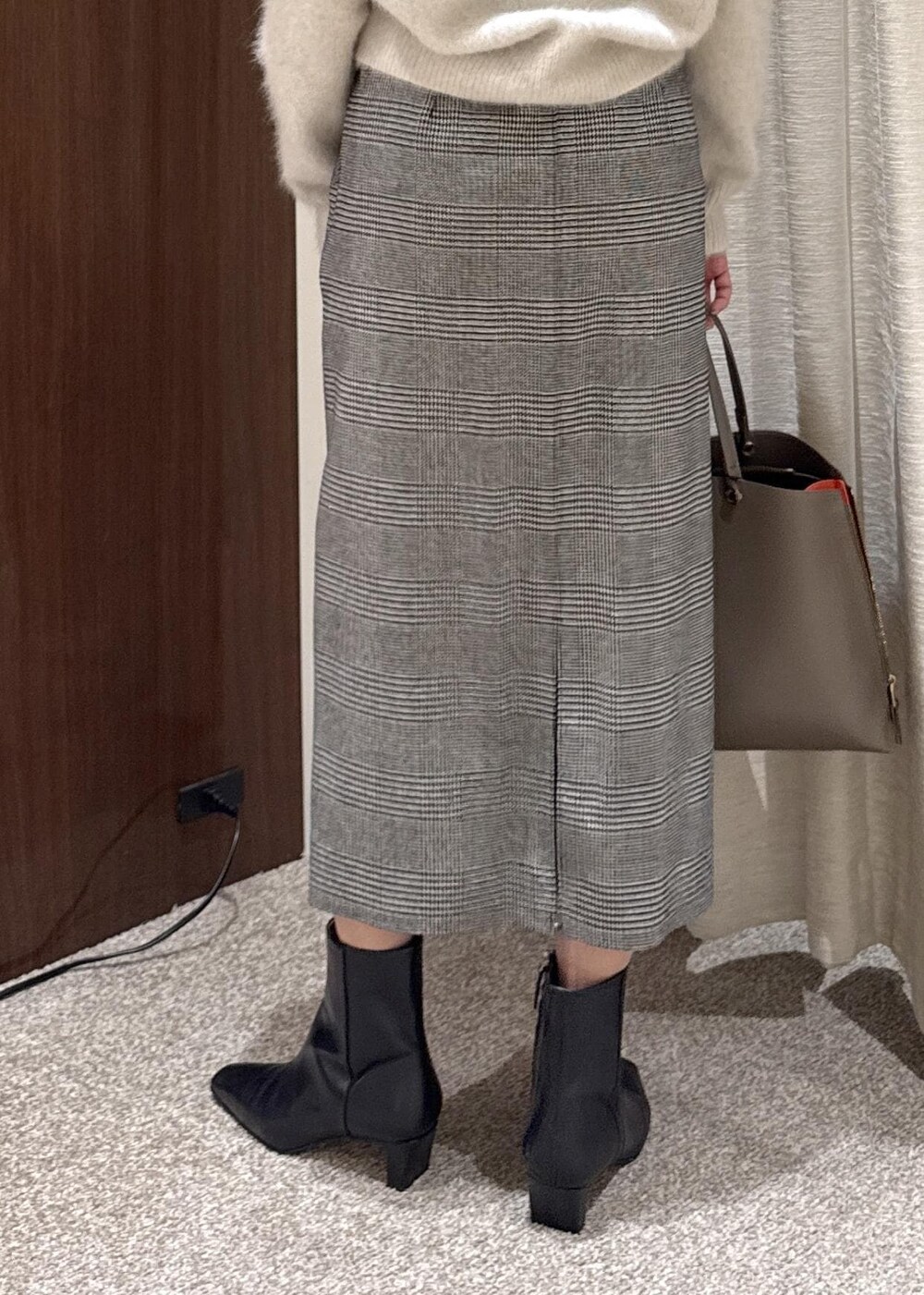 ブラウン系のトートバッグ、ブラック系のブーツ、ブラック系のスカートを着用したレディースの冬コーディネートの6枚目の写真