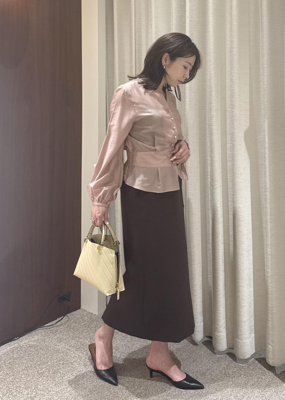 ベージュ系のハンドバッグ、ブラウン系のスカート、ピンク系のシャツ/ブラウスを着用したレディースの春コーディネートの2枚目の写真