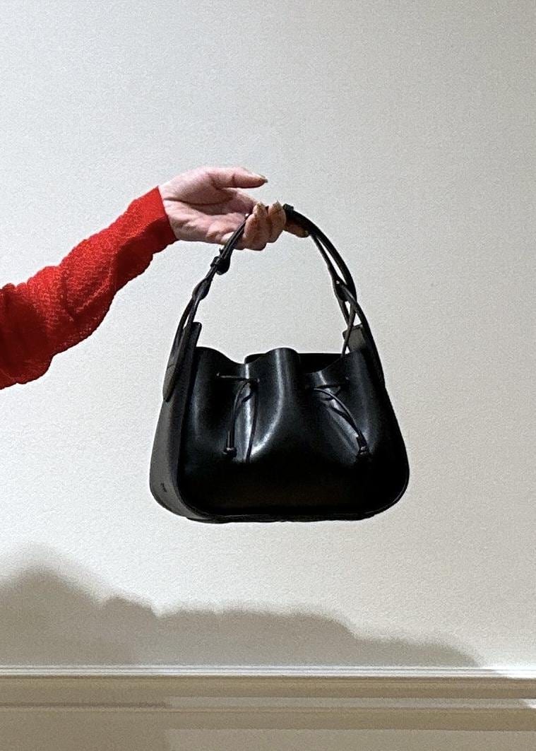 ブラック系のショルダーバッグ、ブラック系のパンプス、ホワイト系のスカートを着用したレディースの春コーディネートの7枚目の写真