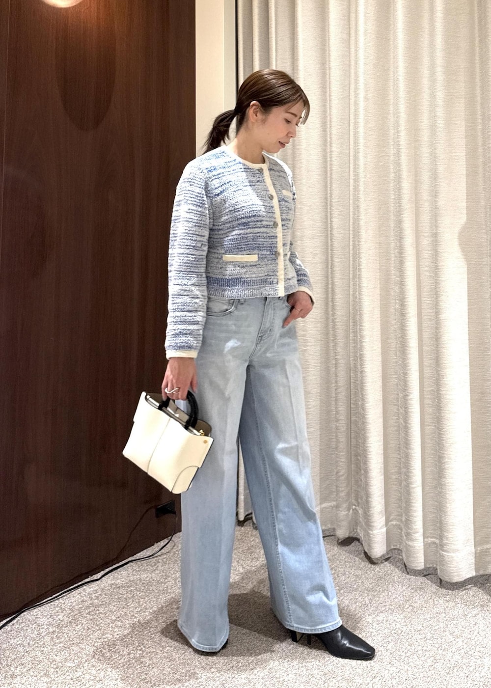 ブラック系のブーツ、ホワイト系のハンドバッグを着用したレディースの冬コーディネートの2枚目の写真