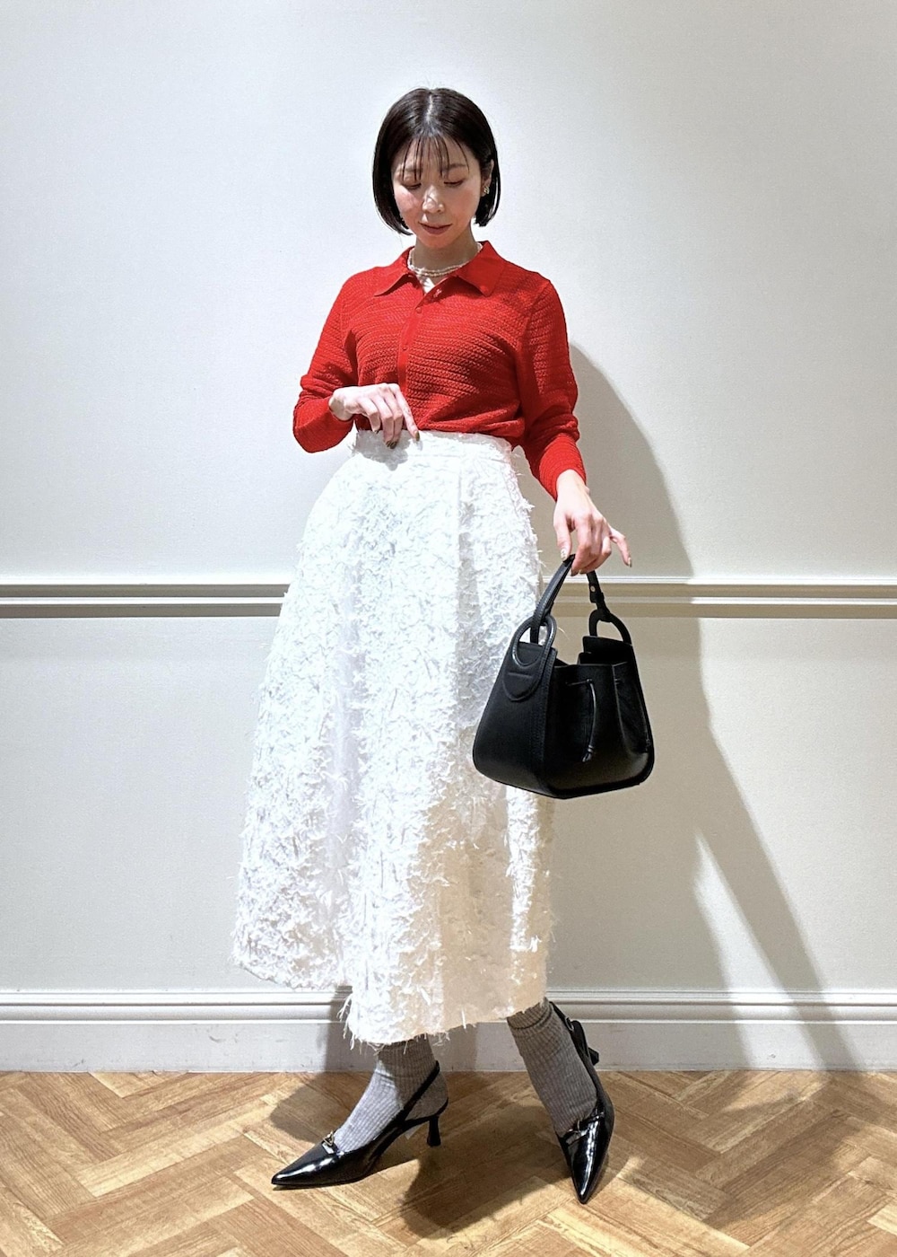ブラック系のショルダーバッグ、ブラック系のパンプス、ホワイト系のスカートを着用したレディースの春コーディネートの4枚目の写真