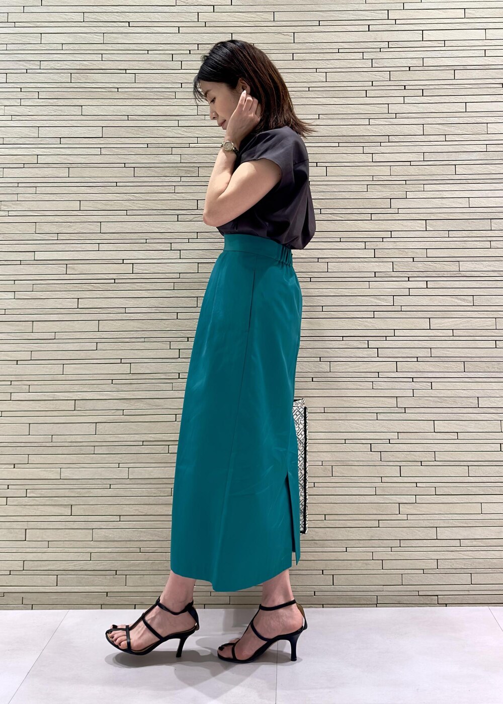 ブラック系のトートバッグ、ブラウン系のシャツ/ブラウス、グリーン系のスカートを着用したレディースの夏コーディネートの2枚目の写真