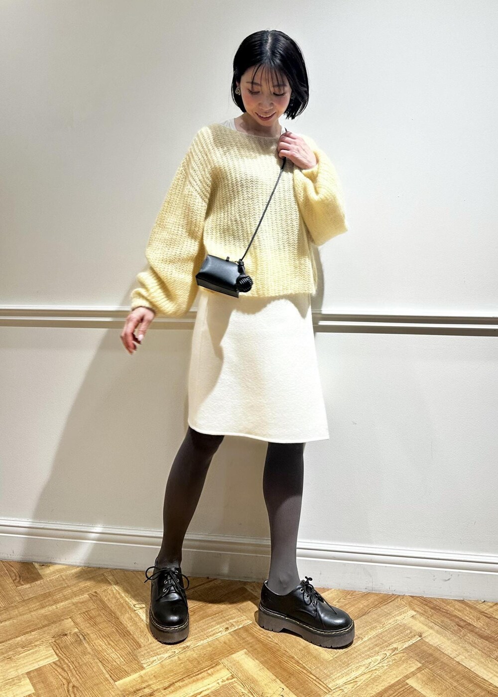 ホワイト系のスカート、イエロー系のニット/セーター、ホワイト系のTシャツ/カットソーを着用したレディースの冬コーディネートの2枚目の写真