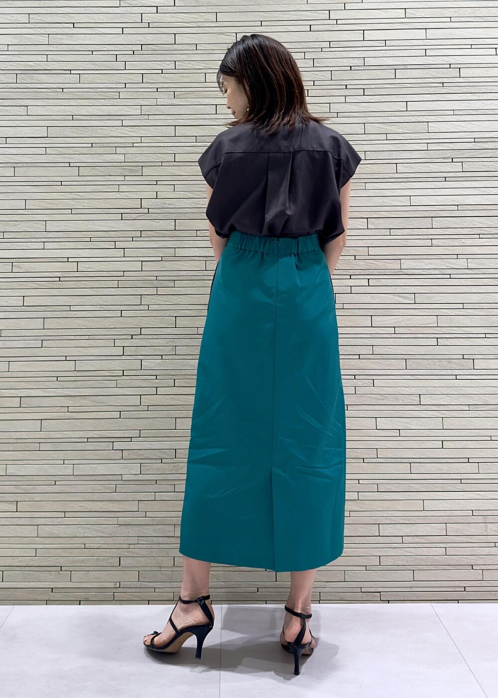 ブラック系のトートバッグ、ブラウン系のシャツ/ブラウス、グリーン系のスカートを着用したレディースの夏コーディネートの3枚目の写真