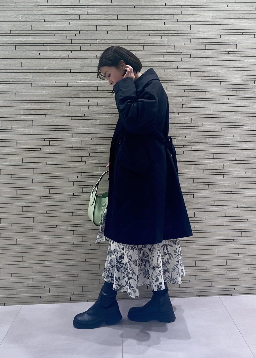 グリーン系のハンドバッグ、ブラック系のダウンジャケット/コート、ブラック系のワンピースを着用したレディースの冬コーディネートの2枚目の写真