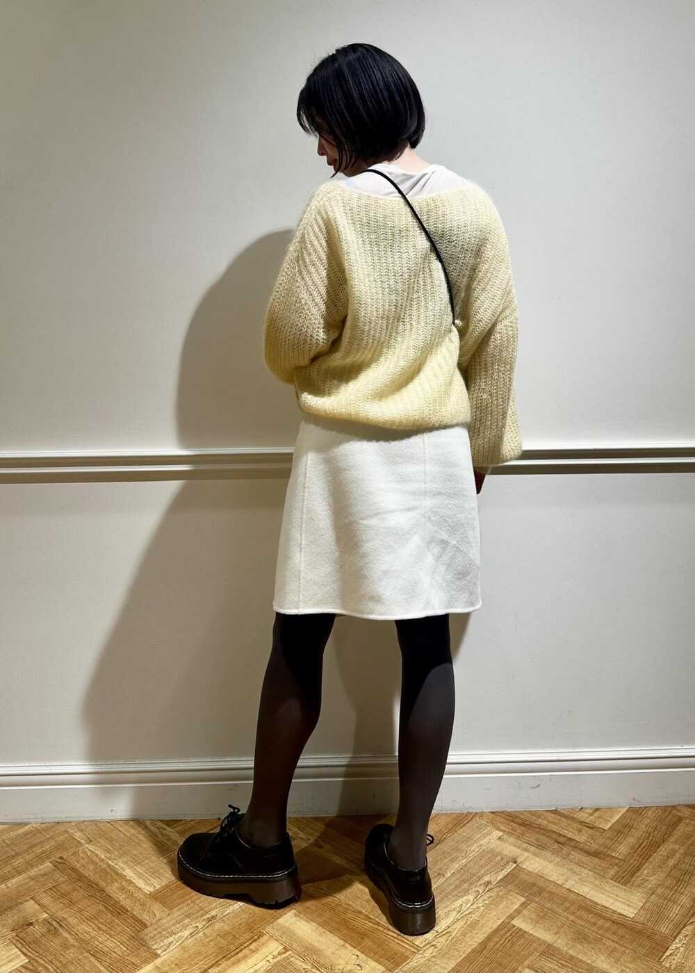 ホワイト系のスカート、イエロー系のニット/セーター、ホワイト系のTシャツ/カットソーを着用したレディースの冬コーディネートの4枚目の写真