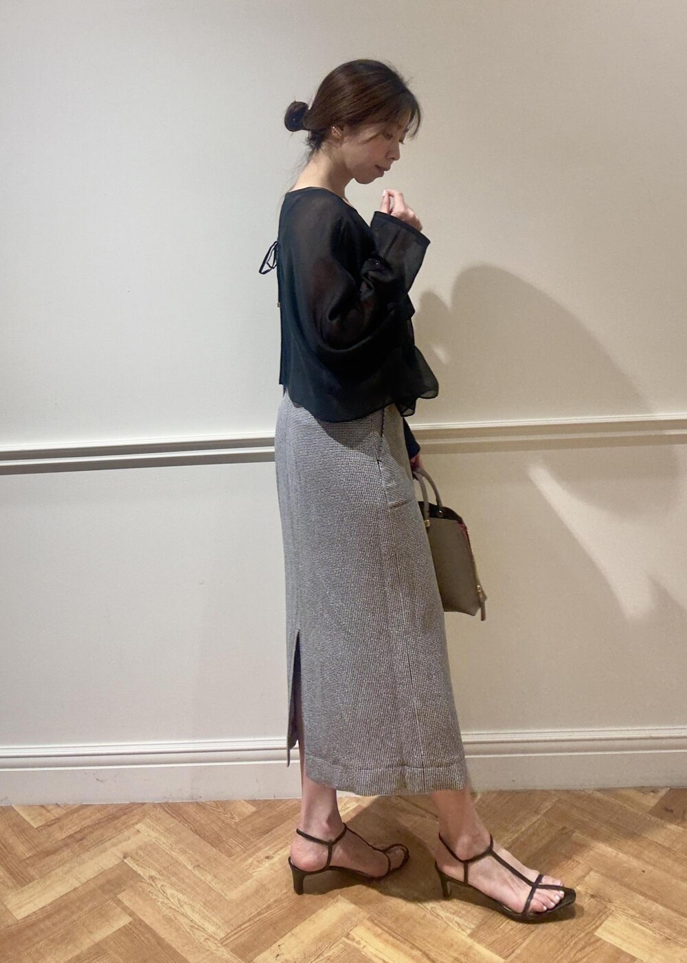 ブラウン系のハンドバッグ、ブラック系のスカート、ブラック系のシャツ/ブラウスを着用したレディースの春コーディネートの2枚目の写真