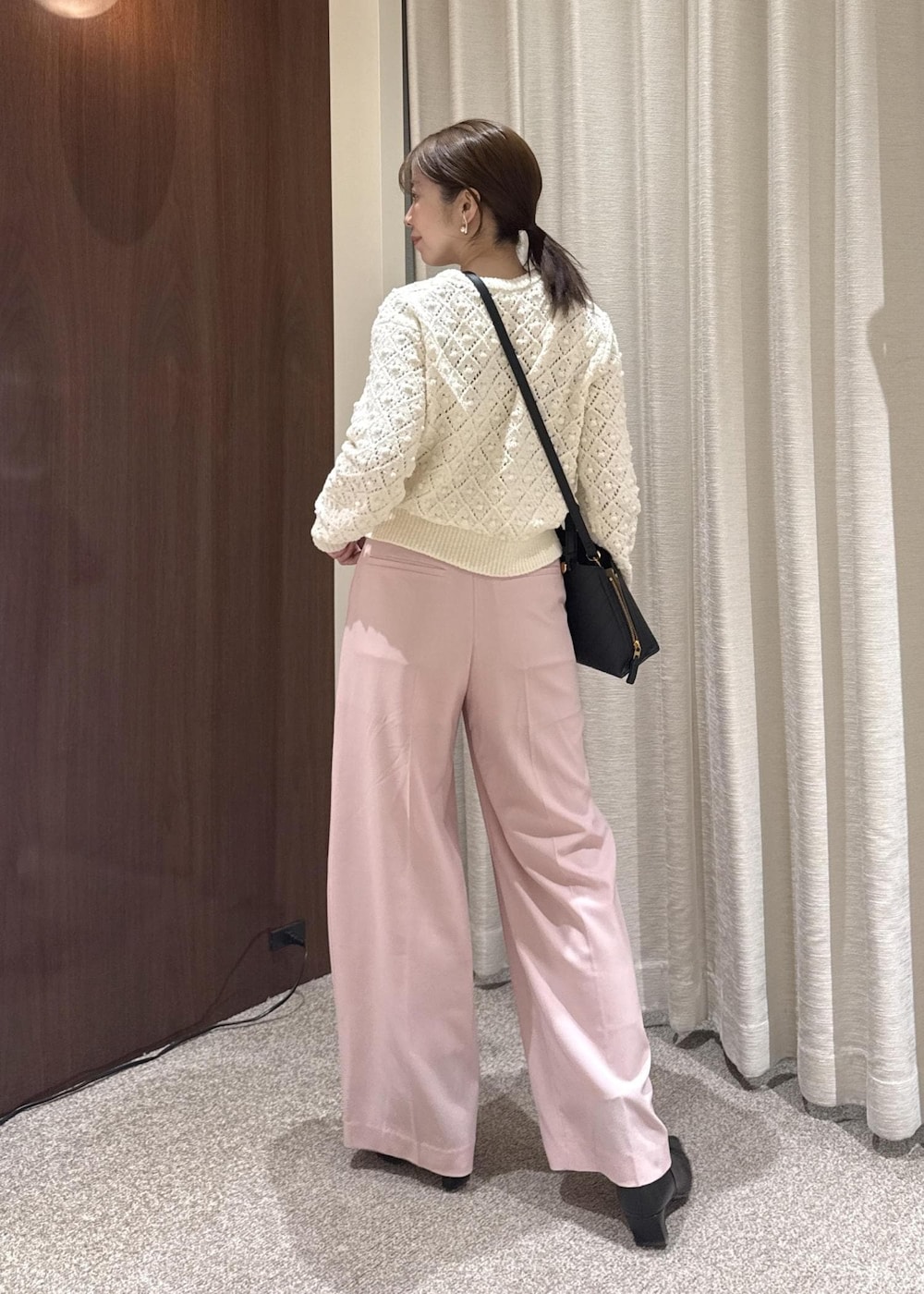 ブラック系のブーツ、ブラック系のハンドバッグ、ホワイト系のニット/セーターを着用したレディースの冬コーディネートの2枚目の写真