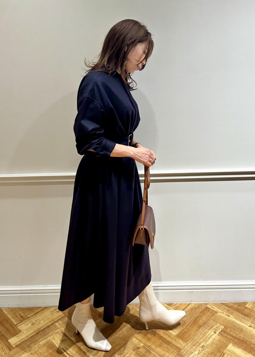 ブラウン系のショルダーバッグ、ホワイト系のブーツ、ブルー系のワンピースを着用したレディースの冬コーディネートの3枚目の写真