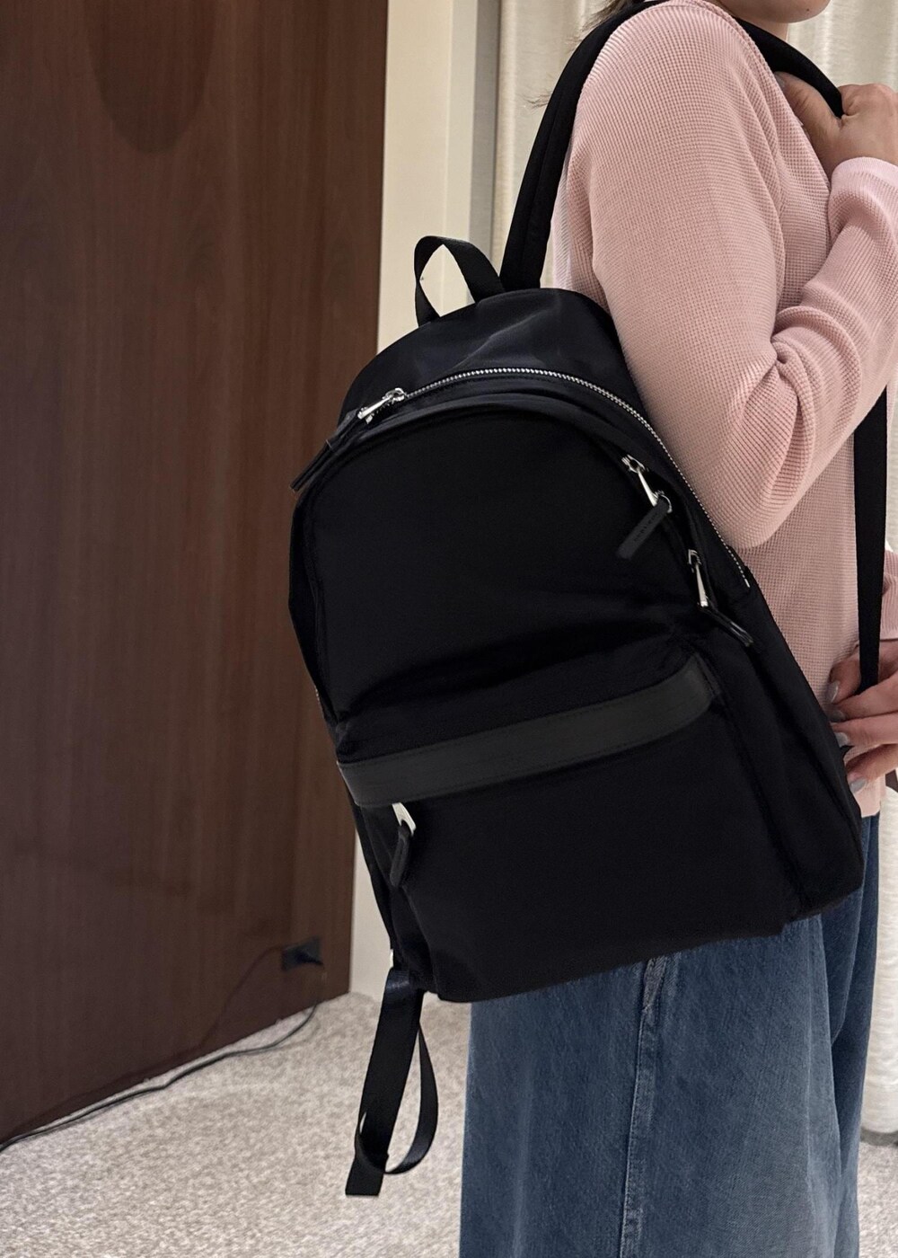 ブルー系のデニムパンツ、ブラック系のブーツ、ブラック系のバックパック/リュックを着用したレディースの冬コーディネートの6枚目の写真