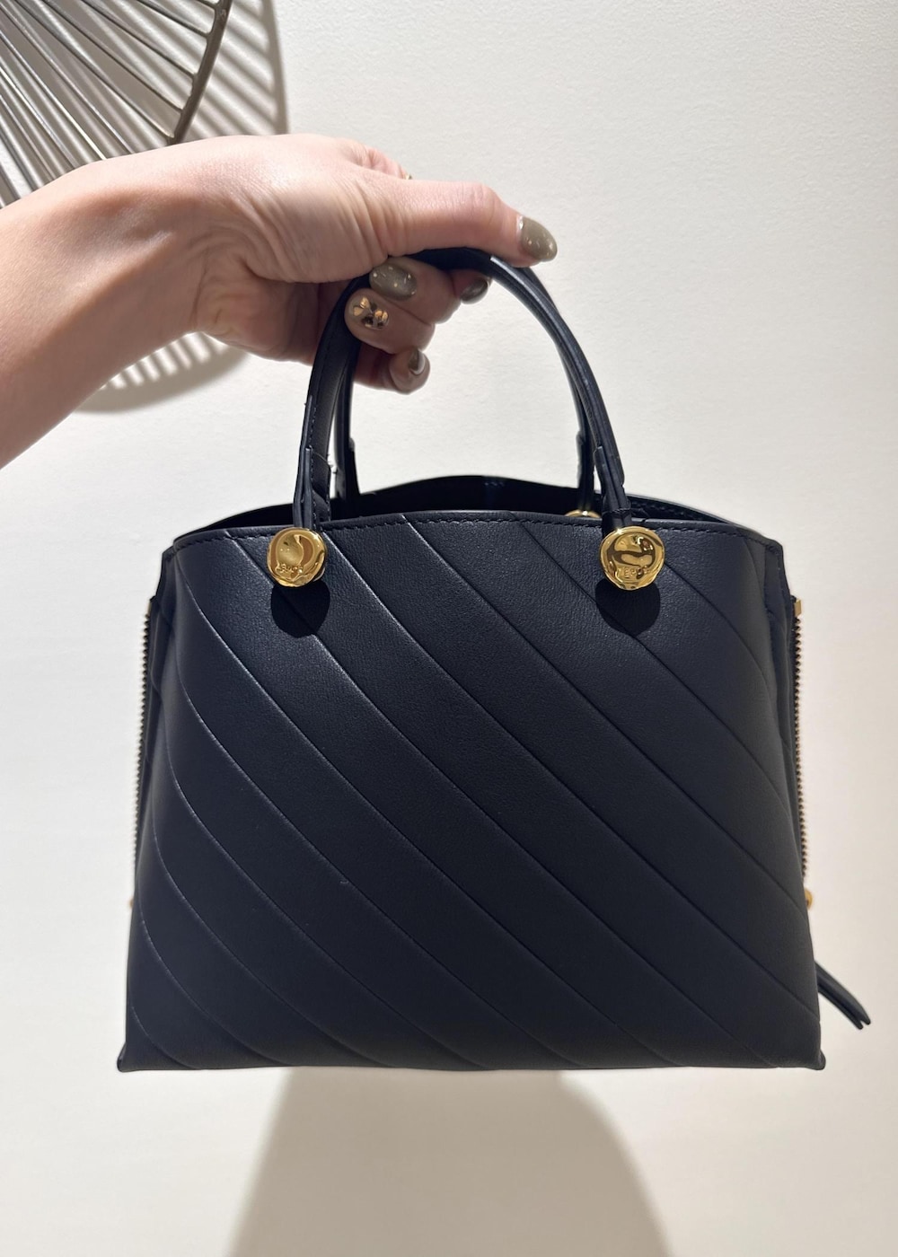 ブラック系のブーツ、ブラック系のハンドバッグ、ホワイト系のニット/セーターを着用したレディースの冬コーディネートの6枚目の写真