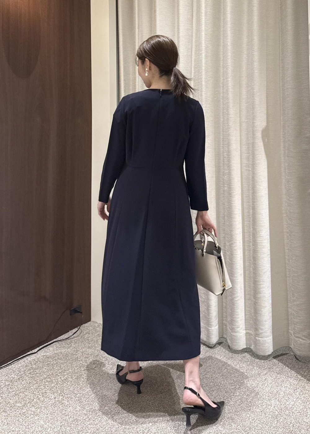 グレー系のハンドバッグ、ブルー系のワンピース、ブラック系のノーカラージャケットを着用したレディースの冬コーディネートの5枚目の写真