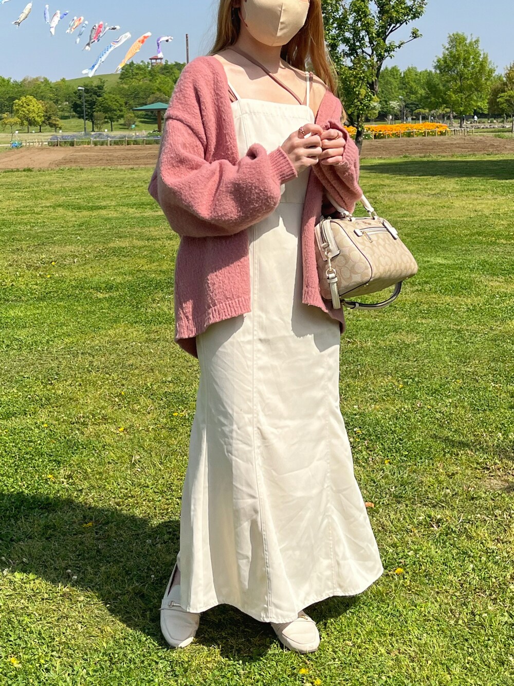 ピンク系のカーディガン/ボレロ、ホワイト系のワンピース、ベージュ系のキャミソールを着用したレディースの春コーディネートの2枚目の写真