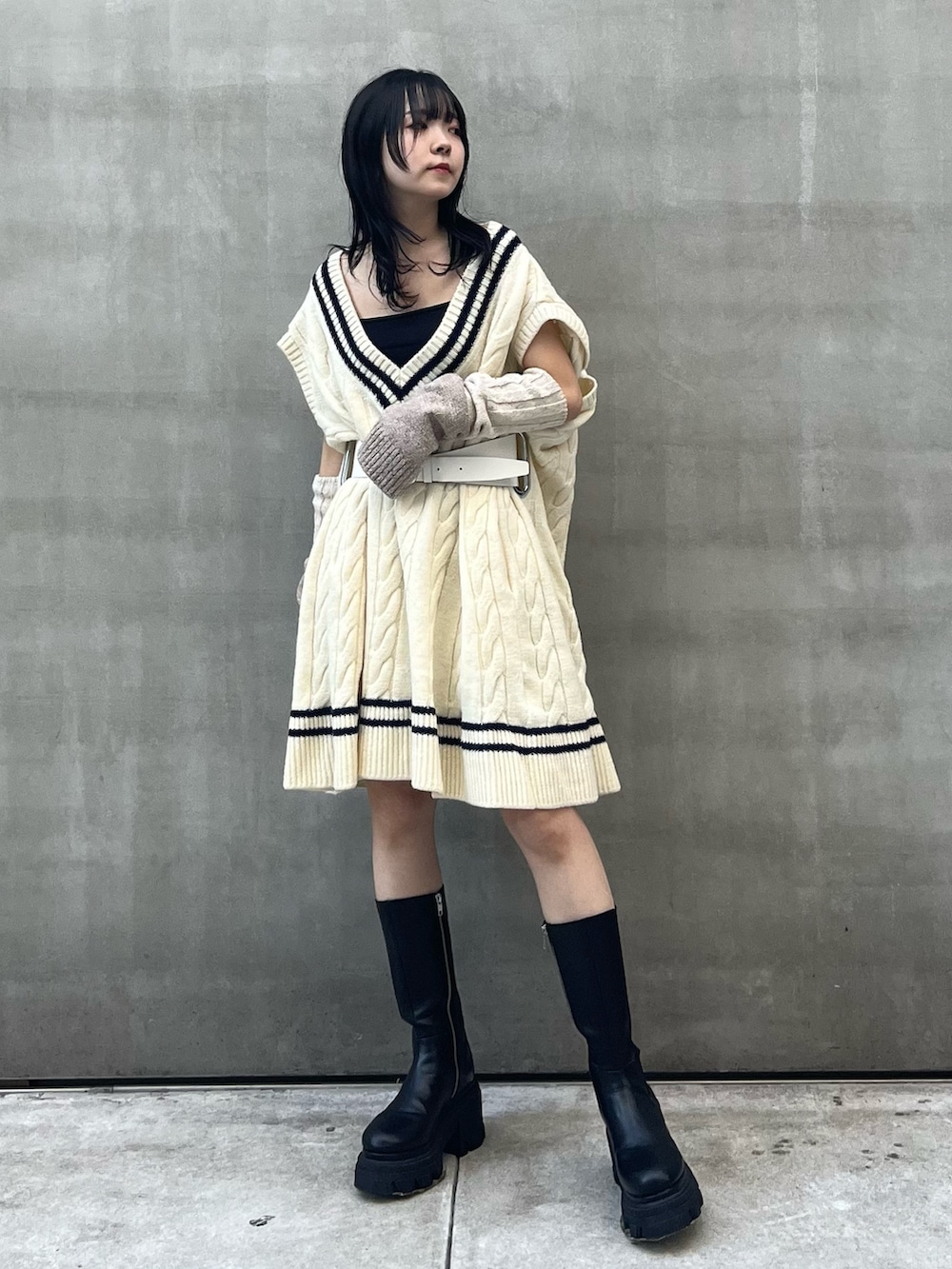 ブラック系のスカート、ブラック系のブーツ、ベージュ系のアームカバーを着用したレディースの秋コーディネートの2枚目の写真