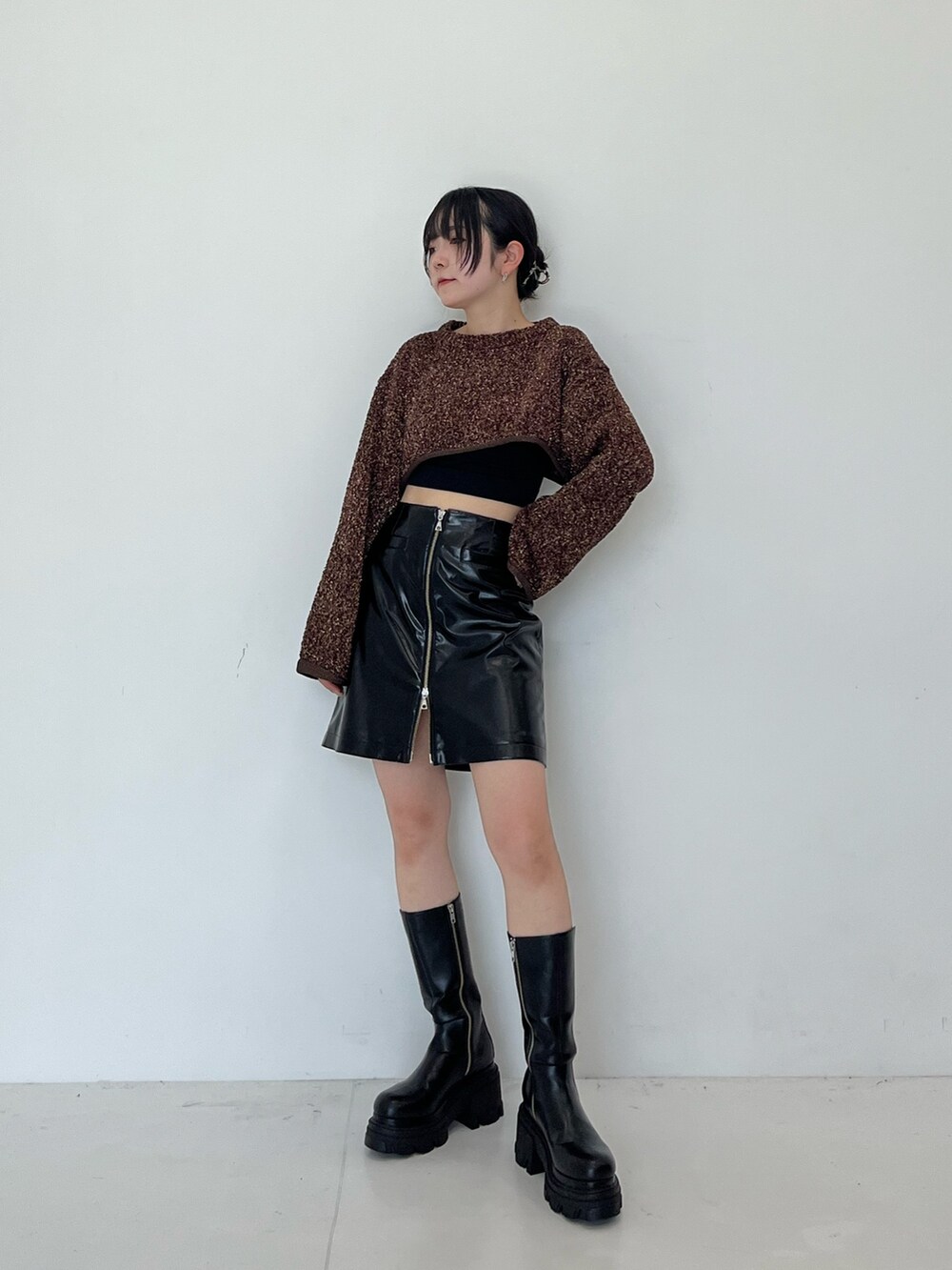 ブラック系のスカート、ブラック系のブーツを着用したレディースの秋コーディネートの2枚目の写真