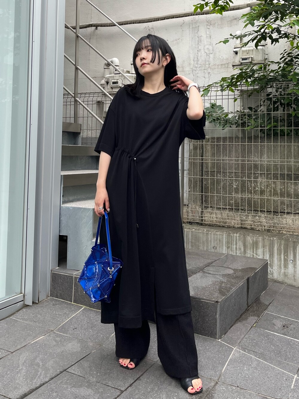 ブラック系のスラックスを着用したレディースの夏コーディネートの2枚目の写真