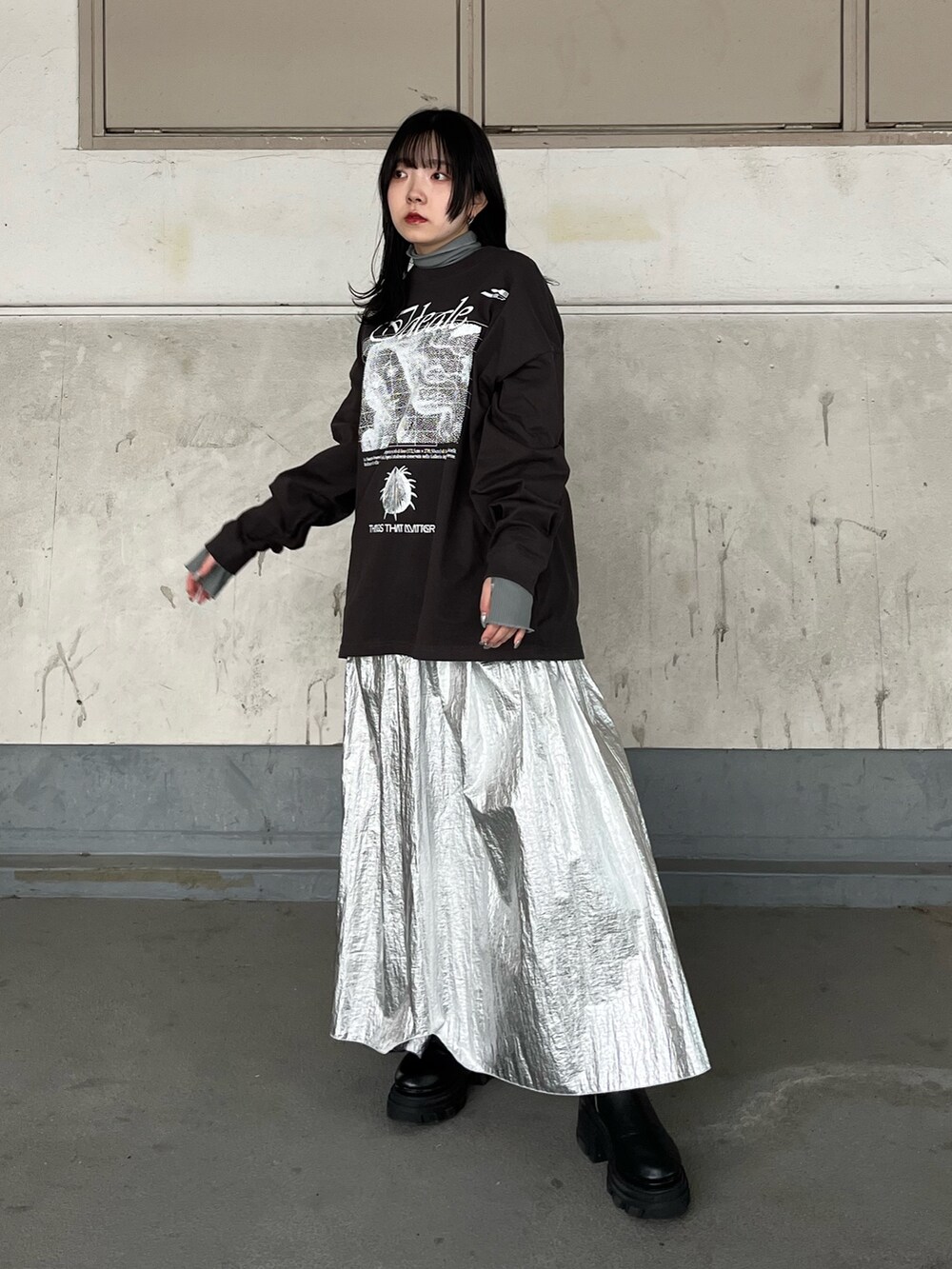 シルバー系のスカート、ブラック系のブーツを着用したレディースの秋コーディネートの2枚目の写真