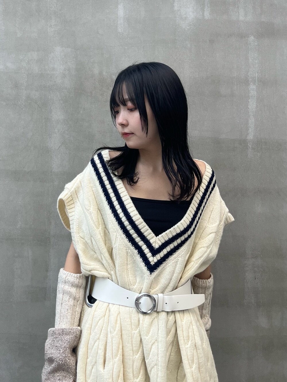 ブラック系のスカート、ブラック系のブーツ、ベージュ系のアームカバーを着用したレディースの秋コーディネートの5枚目の写真