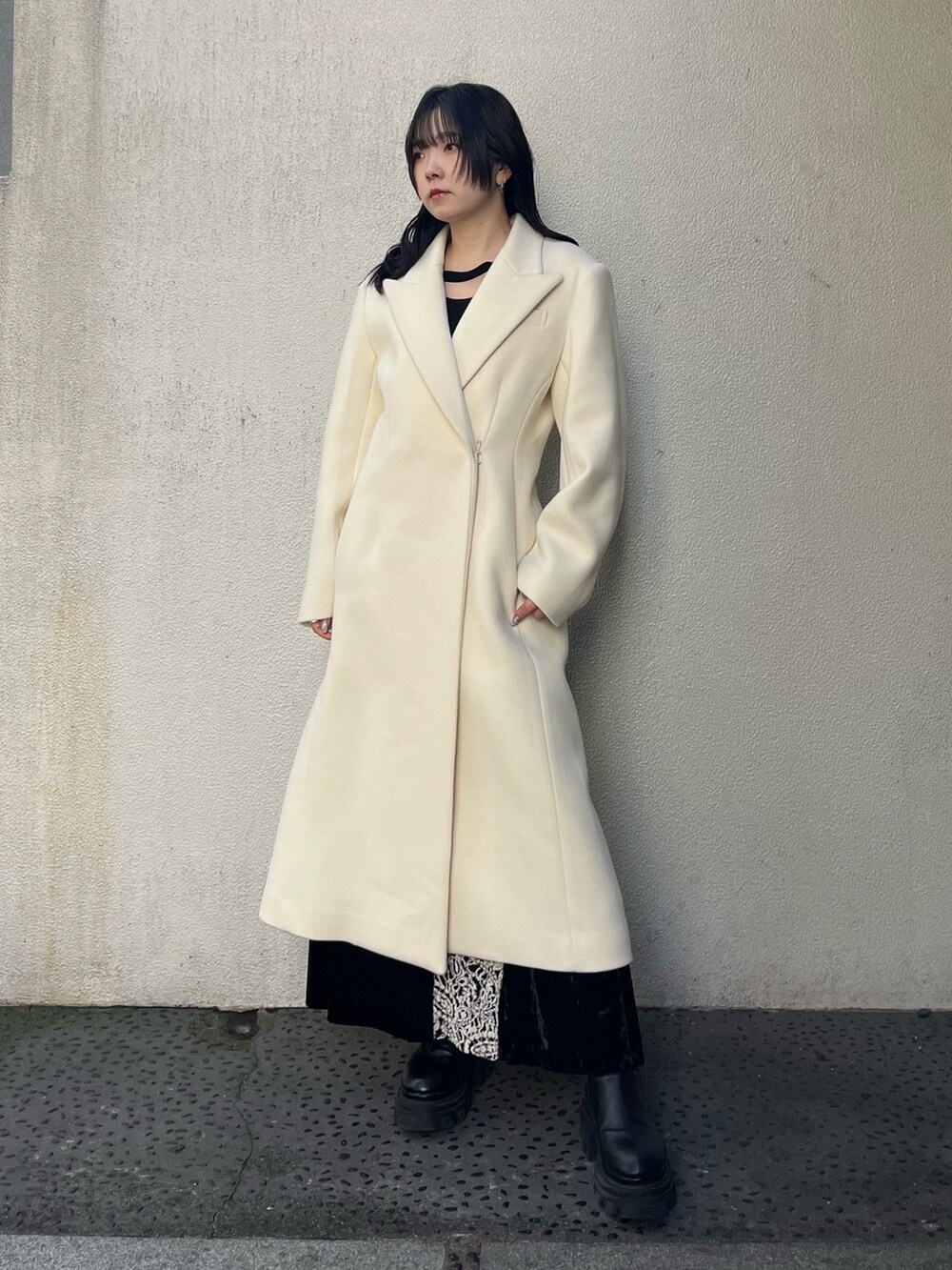 ホワイト系のチェスターコート、ブラック系のブーツを着用したレディースの秋コーディネートの2枚目の写真
